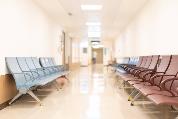 病院の廊下にある待合室には、ぼやけたぼやけた背景として治療を待つ患者のための座席がたくさんあります。 - 病院 ストックフォトと画像