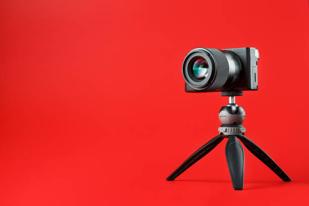 istock Photo video camera with a tripod, on a red background. 2199835932