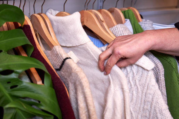 istock a woman takes a white sweater off the rack 2199837109