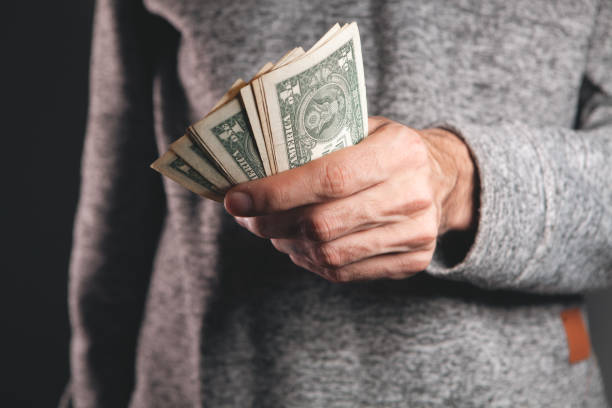 istock man in a black jacket with a pack of dollar bills. 2199837218