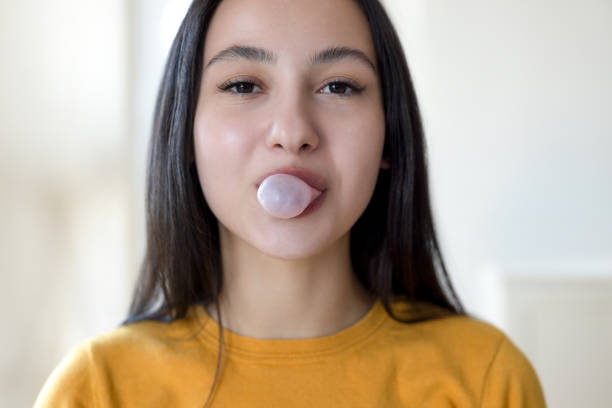 istock Young female chewing gum and blowing 2199841957