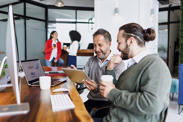 Latin senior man manager and young man employee working together on computer at creative office in Mexico Latin America, hispanic teamwork stock photo