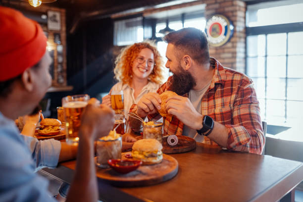 istock Togetherness in Every Bite: Friends Bonding Over Food and Drinks at a Pub 2199847971
