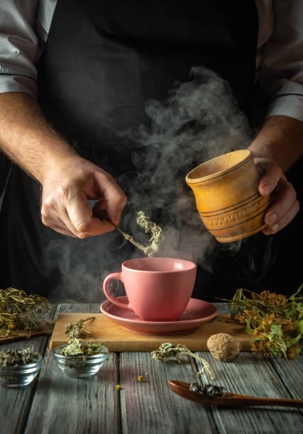 istock Hands carefully prepare a fragrant herbal tea in a charming kitchen, steam rising from the pink cup while fresh herbs and spices are delicately added to enhance the flavor and aroma 2199855433