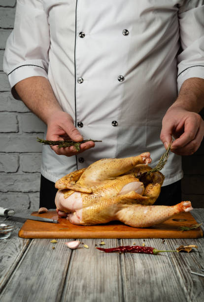 istock A skilled chef expertly seasons a whole chicken, adding fresh herbs and spices while surrounded by a contemporary kitchen. The atmosphere is warm and inviting, perfect for culinary creativity 2199855505