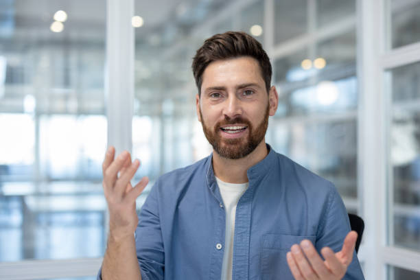 istock Webcam view, man talking looking into camera close up. Businessman at workplace using laptop for video call, smiling at online business meeting conference 2199859726
