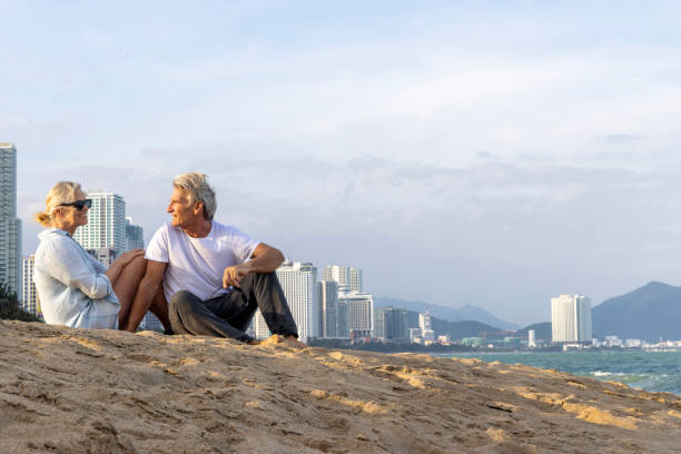 Handsome man relax in sunglasses and straw hat sitting on the tropical beach and looking to the sea.Summer vacations