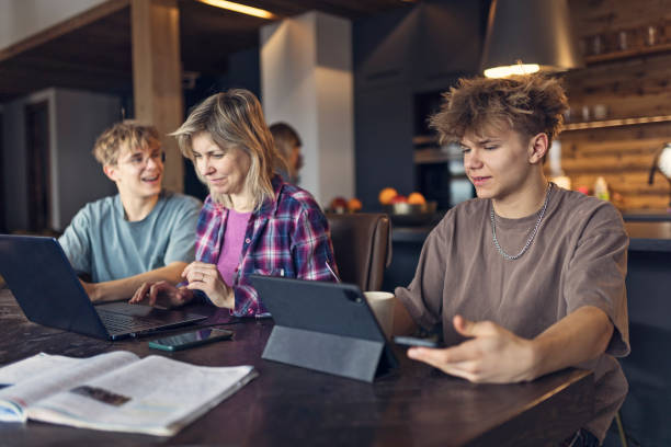 istock Mother working and three teenagers studying together in a cozy interior 2199867298