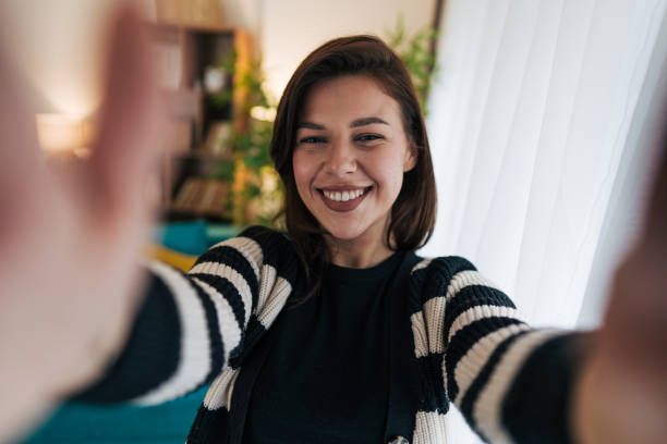 istock Young woman taking a selfie with open arms at home 2199870260