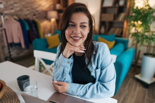 istock Young woman working from home smiling and looking away 2199870388