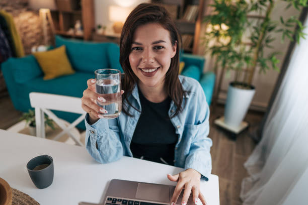istock Young woman drinking water while working from home 2199870393