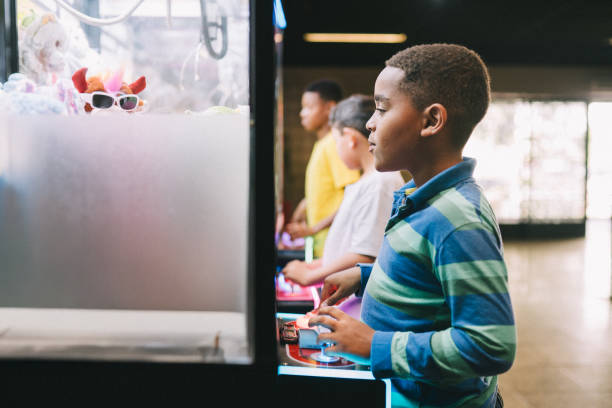 Boy playing with a claw machine trying to pick a stuffed animal at the mall's arcade