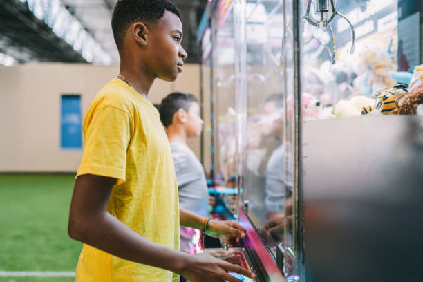istock Teenager boy playing with a claw machine at the arcade 2199871120