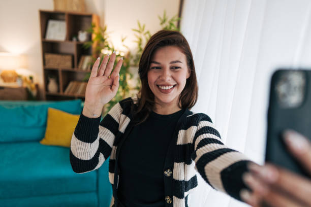 istock Young woman waving hand while making a video call at home 2199871487