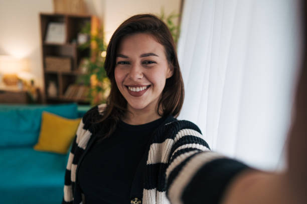 istock Young woman taking a selfie at home smiling at the camera 2199871641