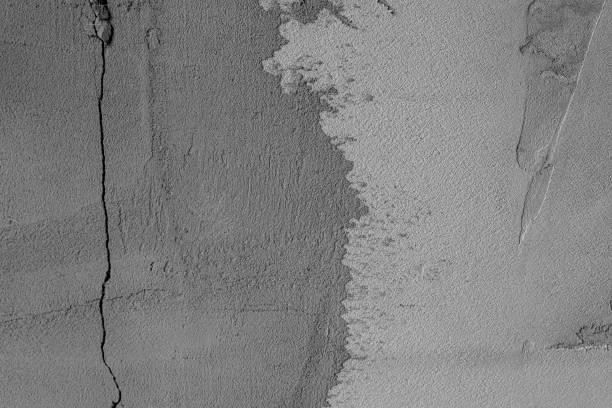 Detailed view of a weathered gray concrete wall with visible cracks and textures.