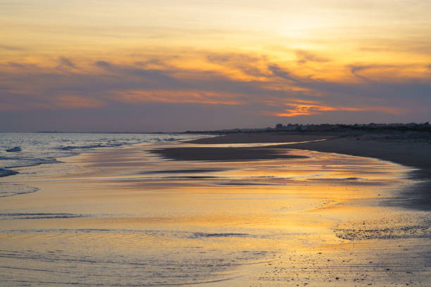 istock Tranquil shoreline bathed in warm hues as the sun sets over the ocean. 2199879151
