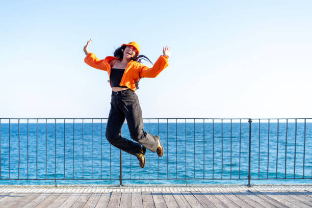 istock Cheerful young woman jumping on the beach 2199879755