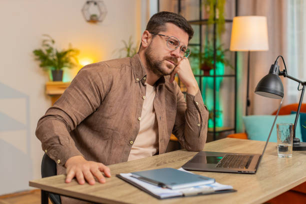 istock Sad Caucasian young man freelancer looks pensive thinks over life concerns sitting at desk at home 2199889359