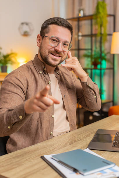 istock Young Caucasian businessman using laptop asking to make telephone conversation, gesturing call me 2199889368