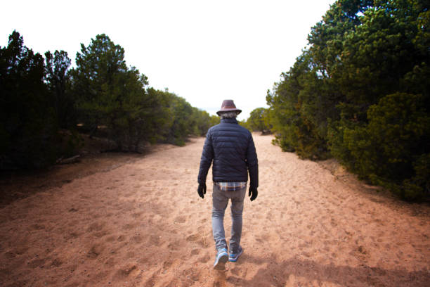 Santa Fe, NM: Senior Man Hiking in Sandy Arroyo in Winter