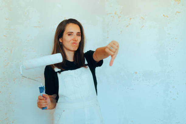 Young woman artist smiling and holding a spray paint can by a colorful graffiti wall in an abandoned urban area