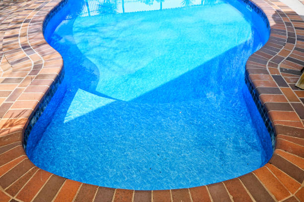 istock A clear, but aging backyard, saltwater pool with paving around the edge. The pool has had the liner replaced. Pool fencing. Pool edge. Pool reflections. 2199909842