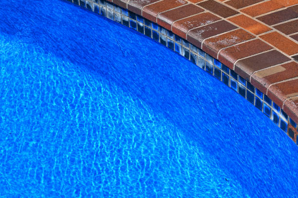 istock A clear, but aging backyard, saltwater pool with paving around the edge. The pool has had the liner replaced. Pool fencing. Pool edge. Pool reflections. 2199909885