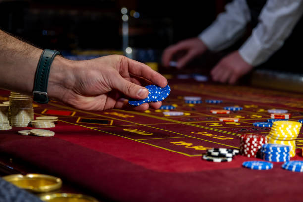 istock Man playing at the roulette table. A close-up vibrant image of multicolored casino table with roulette in motion, with casino chips. the hand of croupier. 2199910066