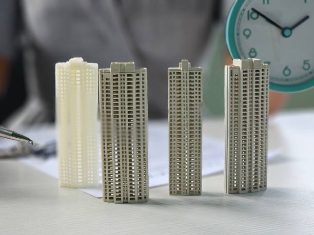 istock Miniature models of skyscrapers displayed alongside a clock and documents on a workspace concept 2199915110