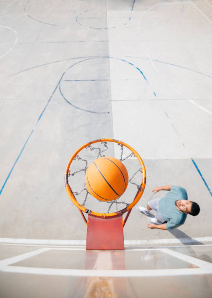 istock Basketball entering the hoop with player watching from below 2199916023