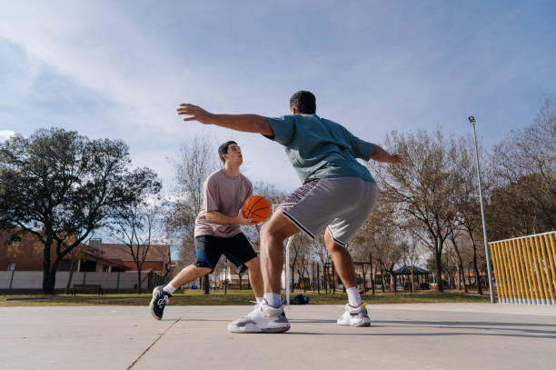 istock Two young men playing basketball outdoors on a sunny day 2199916027