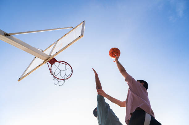 istock Two young men playing basketball outdoors on a sunny day 2199916070