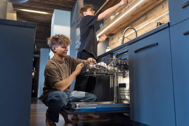 istock Two teenage boys unloading a dishwasher in a modern kitchen 2199920021