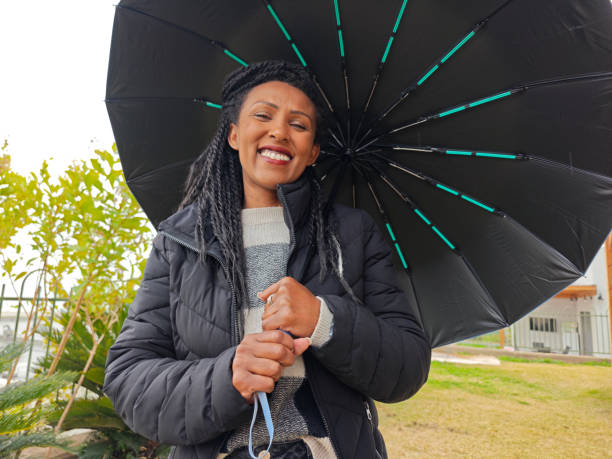 istock Smiling Woman Holding an Umbrella on a Rainy Day. 2199920936