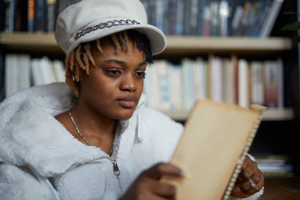 istock young African descent lady reading book at cafe 2199921836
