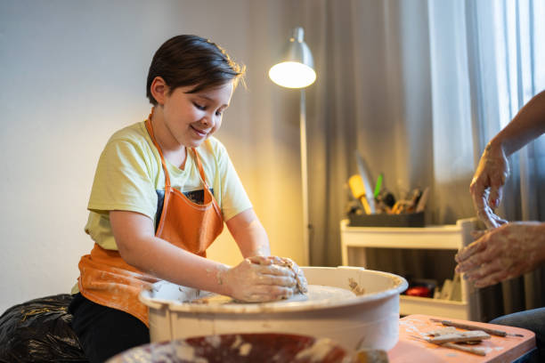 istock 10-year-old child is learning to use the pottery wheel with instructor. 2199923985