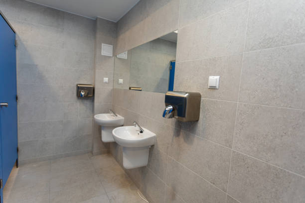 A person is lifting the lid of a toilet in a modern bathroom setting.