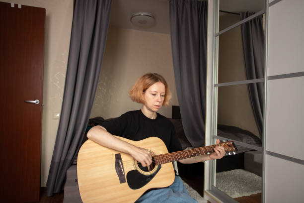istock music lessons, Woman learning guitar, focusing on concentration, practicing new chords, developing her skill as a performer 2199926111