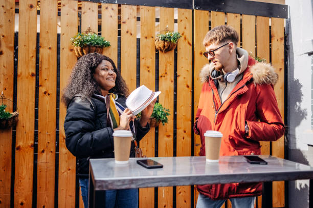 istock University students on a coffee break outdoor at sidewalk cafe trying on hat while having fun 2199928646