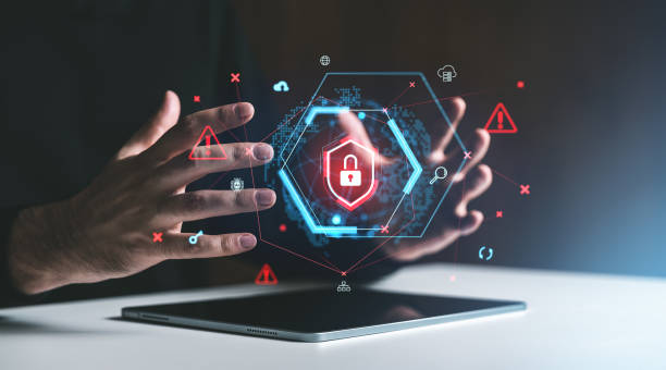 istock Hands surrounding a digital padlock hologram with cybersecurity symbols on a tablet screen. 2199930128