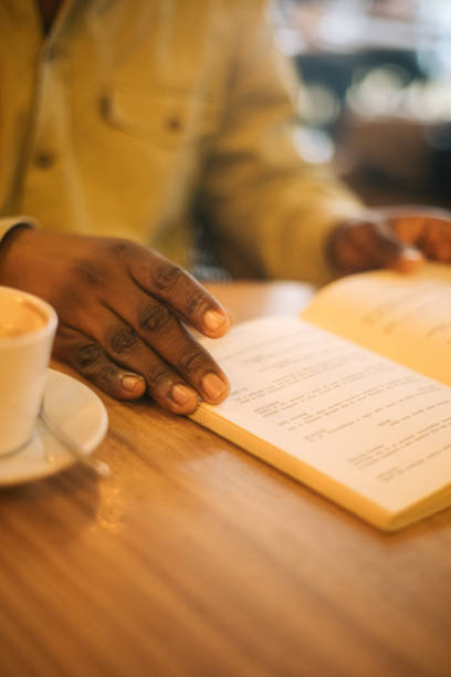 istock Black man hands paging a book in a cafe 2199931965