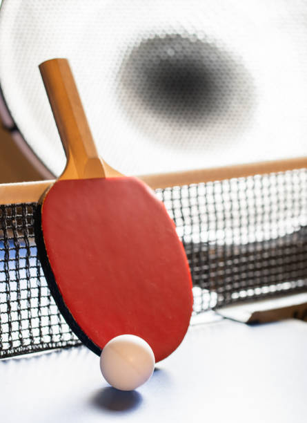 istock Ping pong rackets and balls on a blue table with net. 2199933122