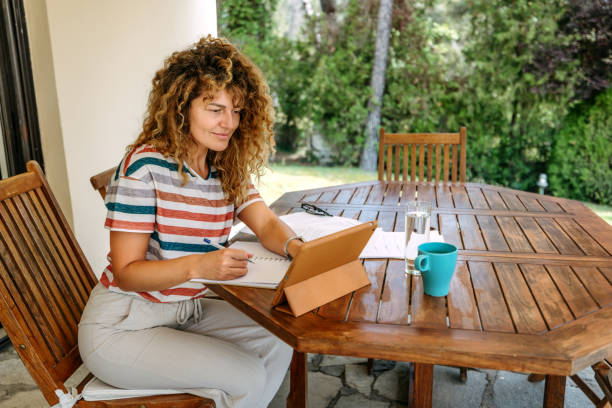 istock Young beautiful woman using digital tablet while working at the back yard of her house 2199935676