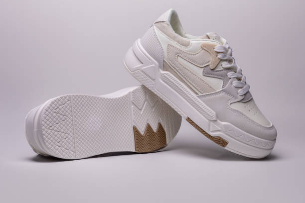 istock Pair of white sneakers leaning on its side showing sole 2199935752