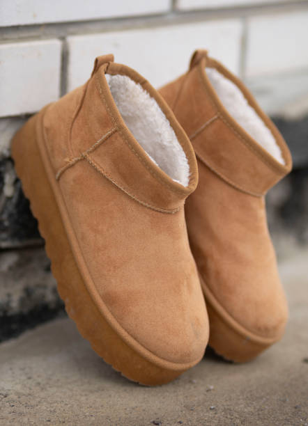 istock Pair of camel-colored winter boots with fur inside leaning against a white wall 2199935831