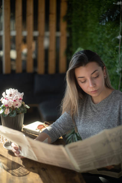istock Beautiful retro woman reading a newspaper in a cafe 2199936084