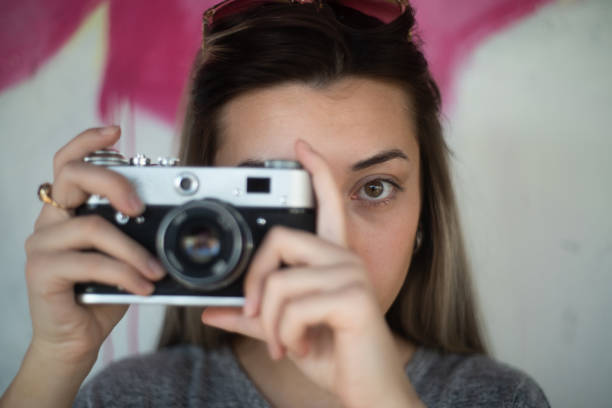 Young and beautiful woman taking photos with a retro camera.