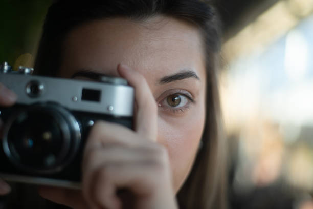 istock Young woman taking photos with a retro camera 2199936331