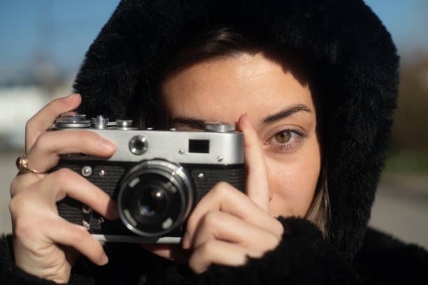 istock Young woman taking photos with a retro camera 2199936341